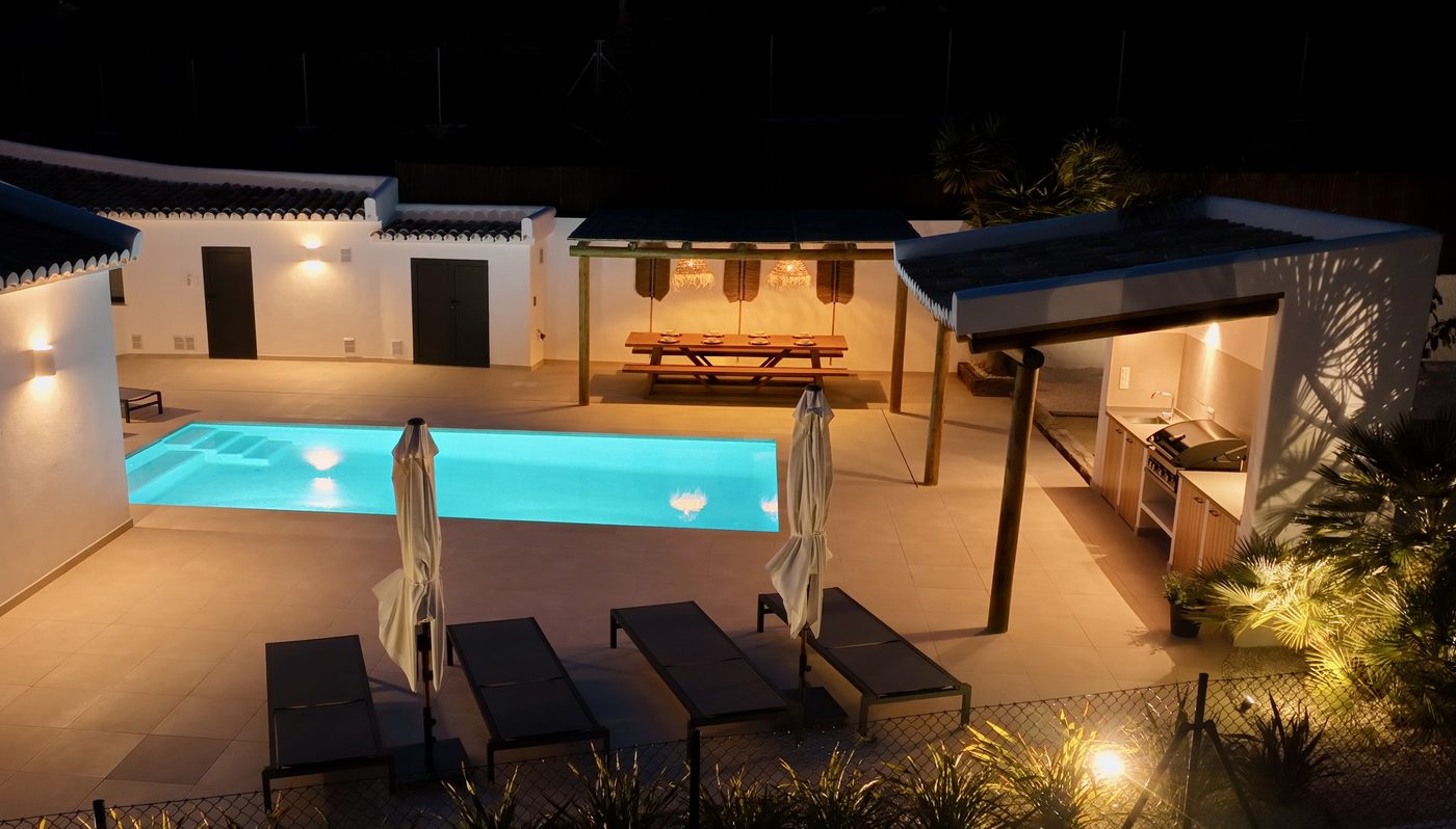 Pool and outdoor lounge at night with summer kitchen illuminated